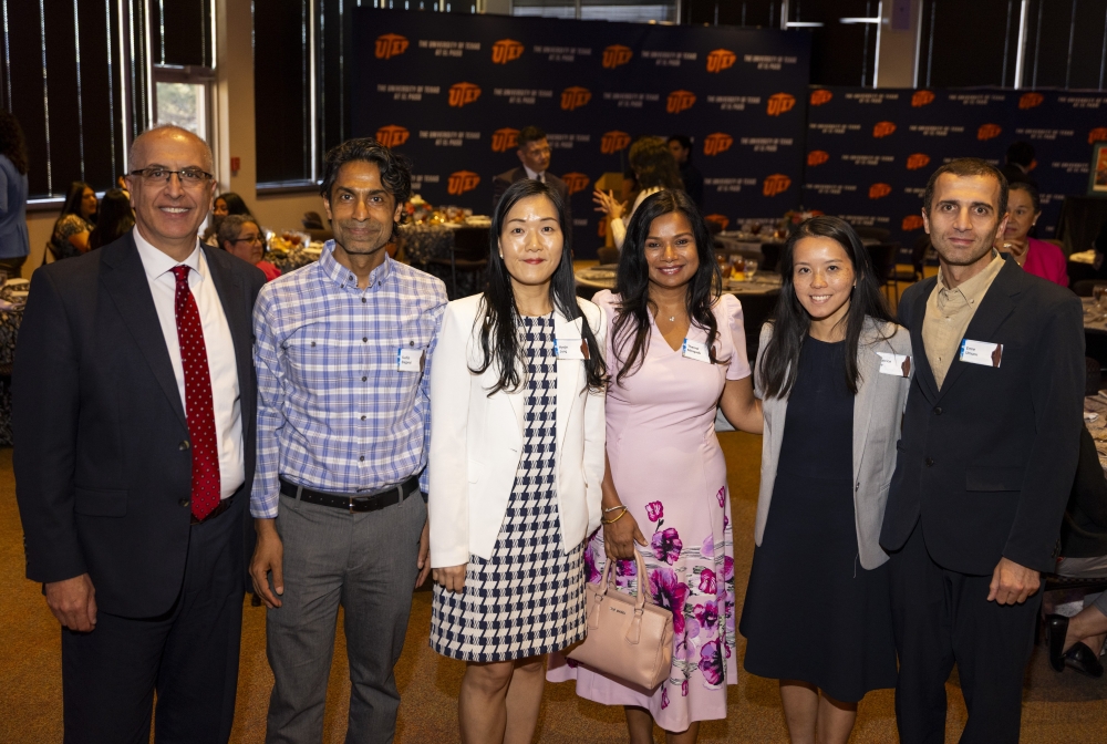 Six attendees pose together in front of a UTEP backdrop at the reception.